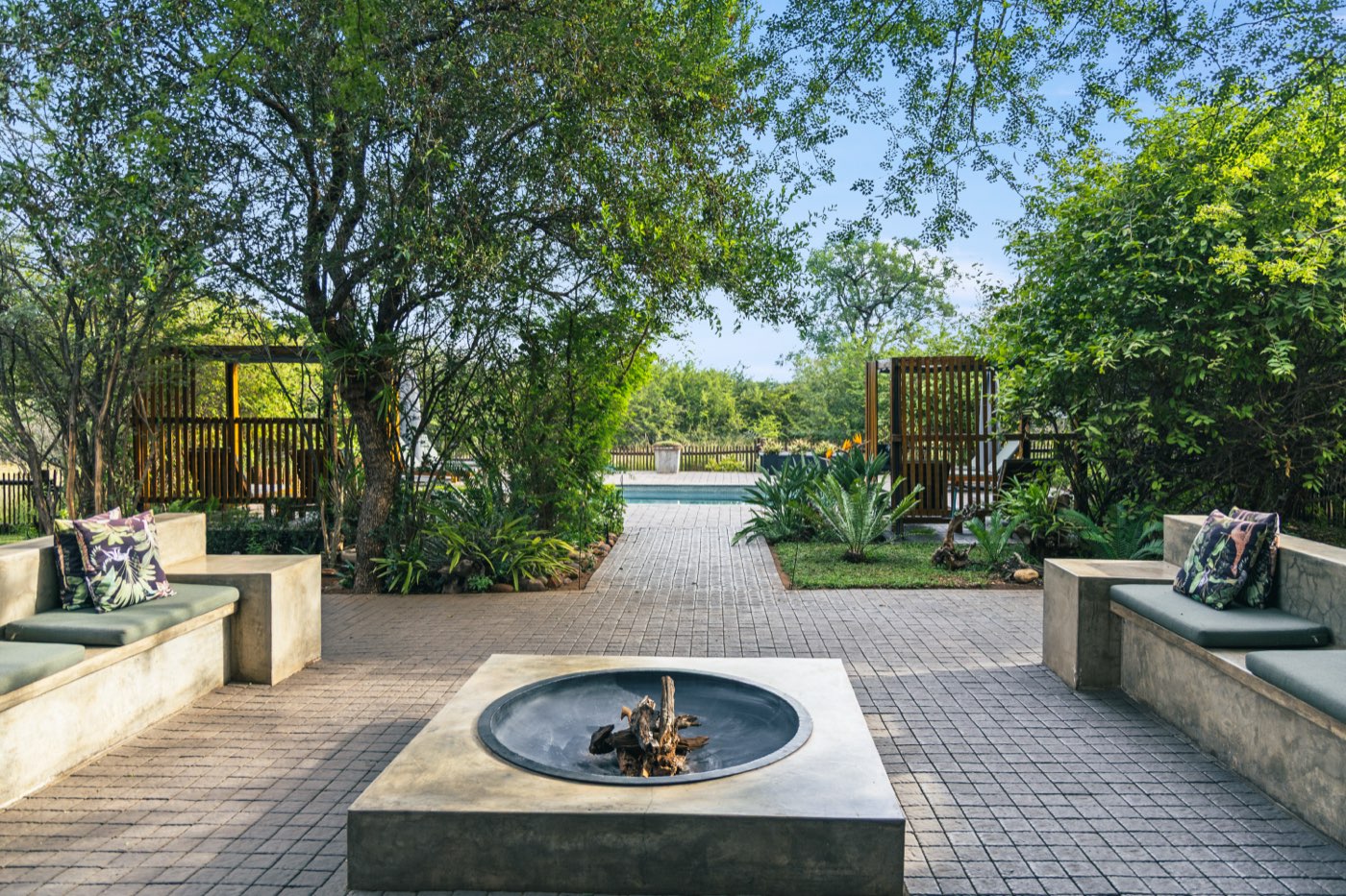 The boma at Muunga — a square concrete fire pit with built-in benches, and a brick path running down towards the pool.