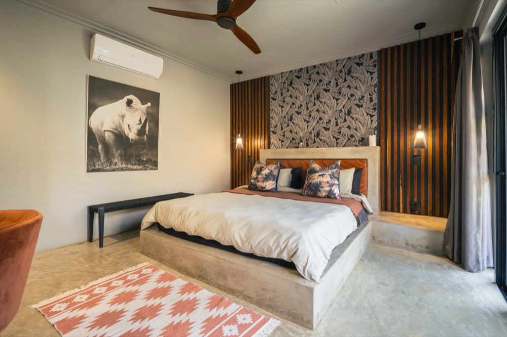 The Deluxe Garden Room with a rhino photograph on the wall and a patterned rug at the foot of the bed.
