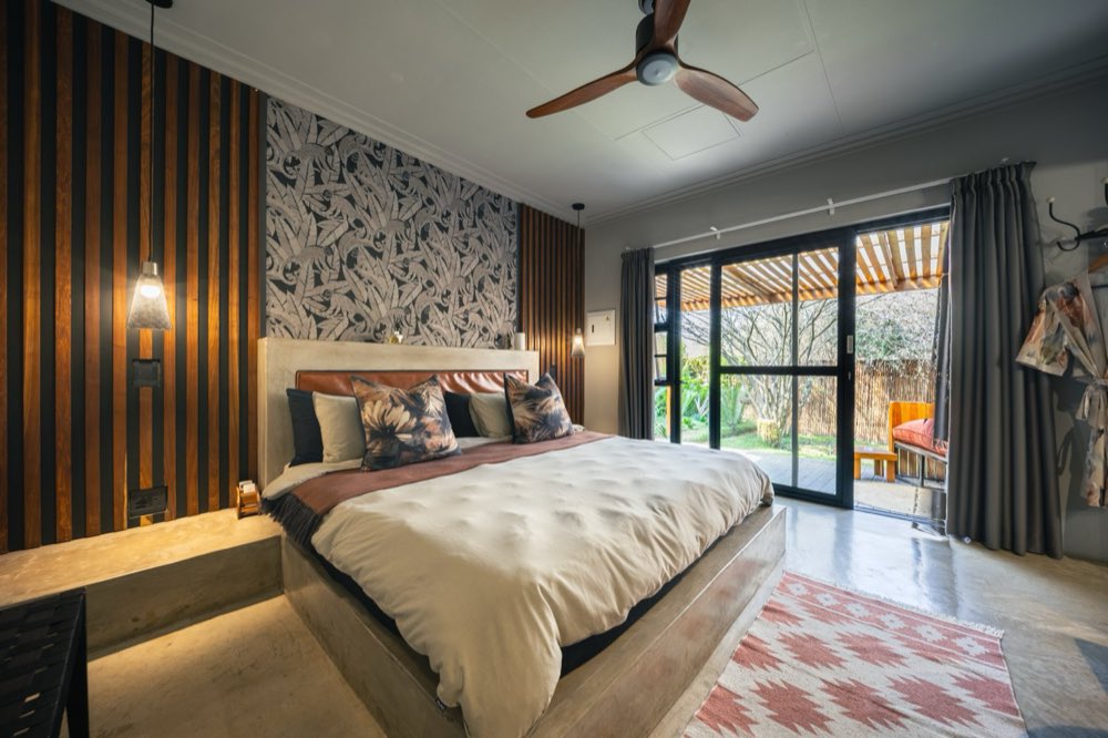 The Deluxe Garden Room bed facing open doors onto the private garden.