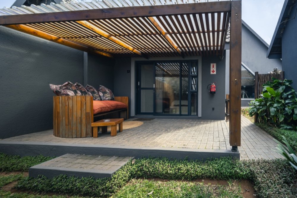 The Deluxe Garden Room's covered patio and day bed seen from the lawn.