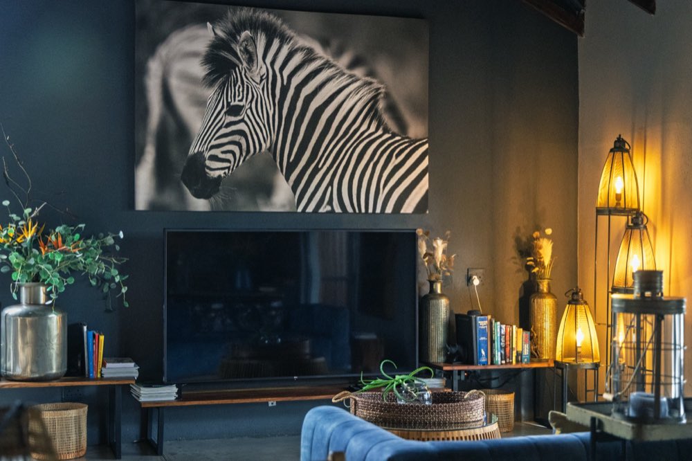 The main lounge after dark with the lanterns lit and Ruan's zebra photograph on the far wall.