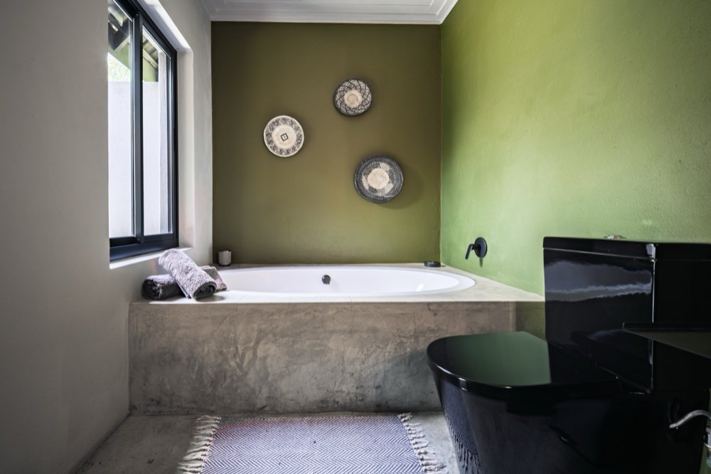 The Superior Bush Suite bathroom — a built-in bath against an olive wall hung with three woven baskets.